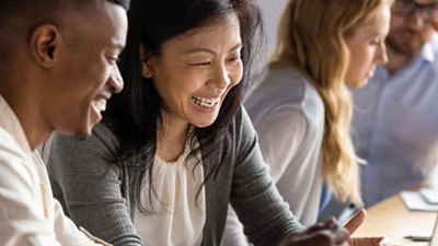 Duas pessoas sentadas frente a frente olhando para a tela de um notebook.