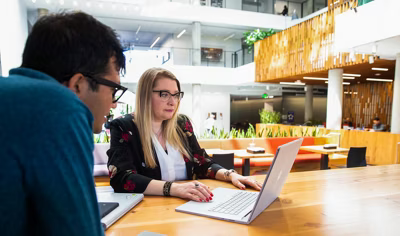 Pessoa sentada no banco de tr&aacute;s de um ve&iacute;culo usando um notebook e olhando para um celular